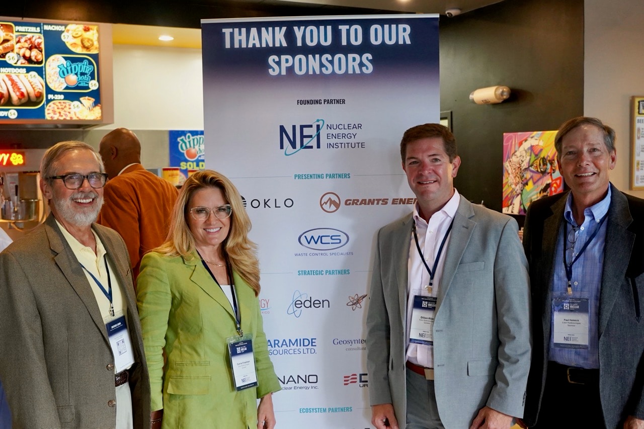 Forum attendees standing in front of the Los Alamos Nuclear Forum sponsor backdrop